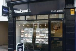 Image shows shop front of Winkworth on a street. The panelling is painted black and the glass front shows images of property inside.