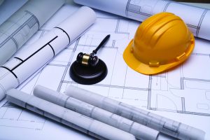 Hard hat and gavel on buidling plans shutterstock_2081842651 Andrey_Popov