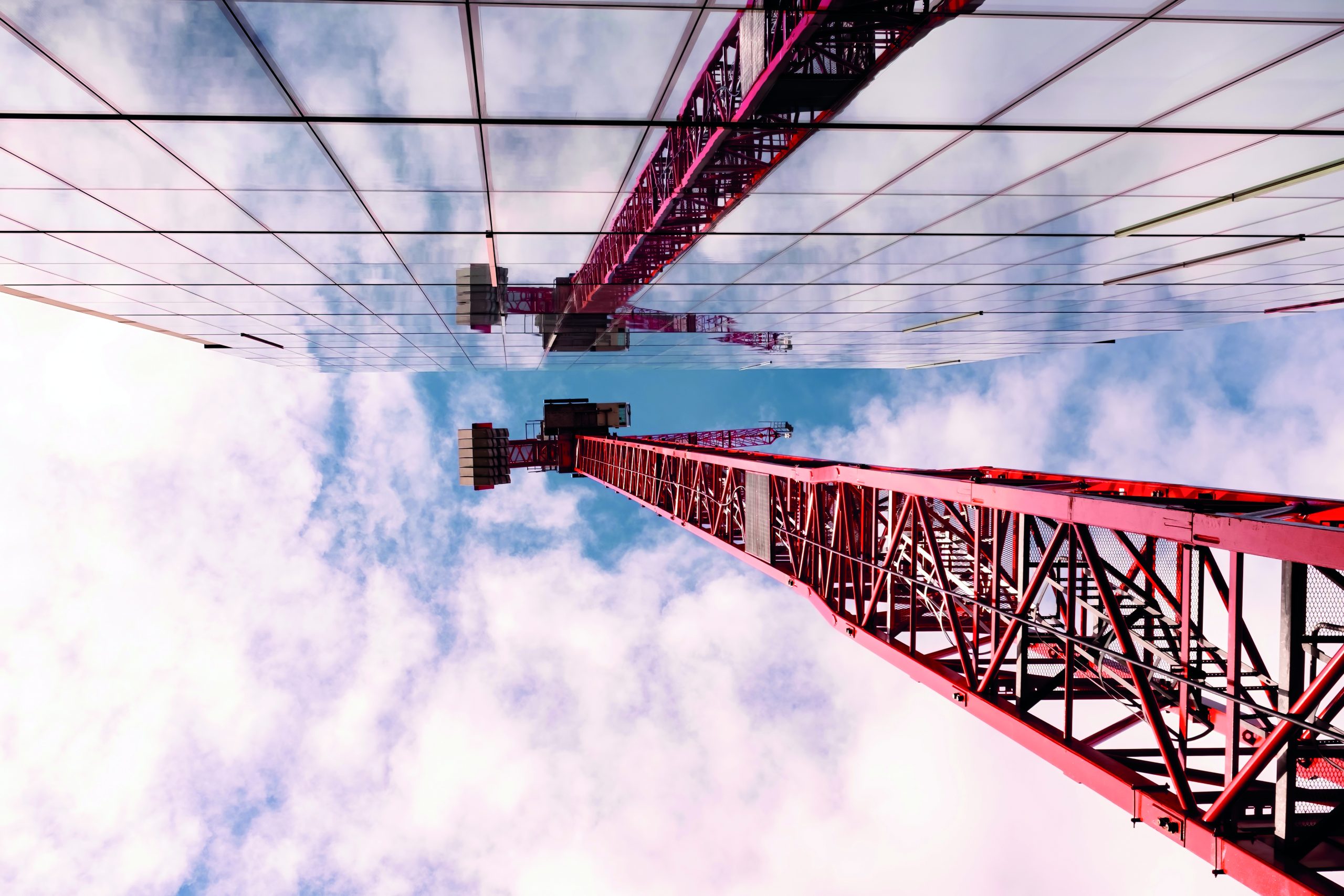 Red crane mirrored against glass building in the City of London. 
