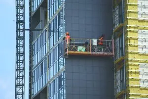 Builders fixing cladding on the outside of a building