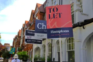 Estate agent 'To let' signs in front of a row of terraced houses in London.