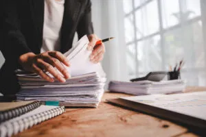Checking-pile-of-papers-on-desk-shutterstock_2533540181-Daenin-300x200.webp