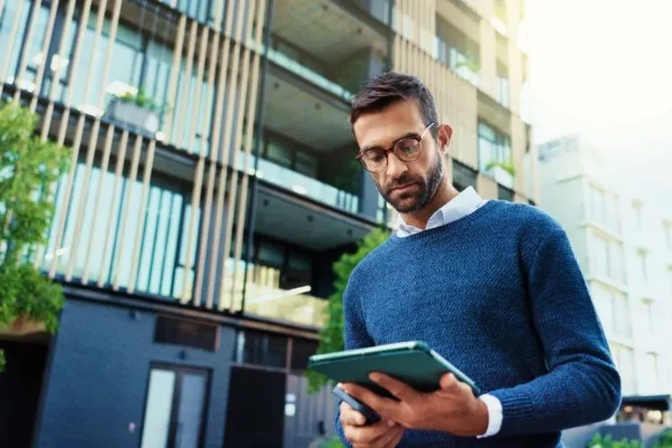 Man-outside-flats-with-tablet-shutterstock_2603761667-PeopleImages-scaled-e1765891056830-748x499.webp
